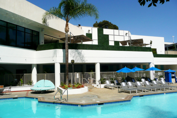 Green hedges on a second floor with a pool down below